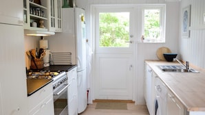 A compact kitchen with white cabinetry, a stove, a sink, and a window. - 4 Person Holiday Home in Blokhus (Blokhus)