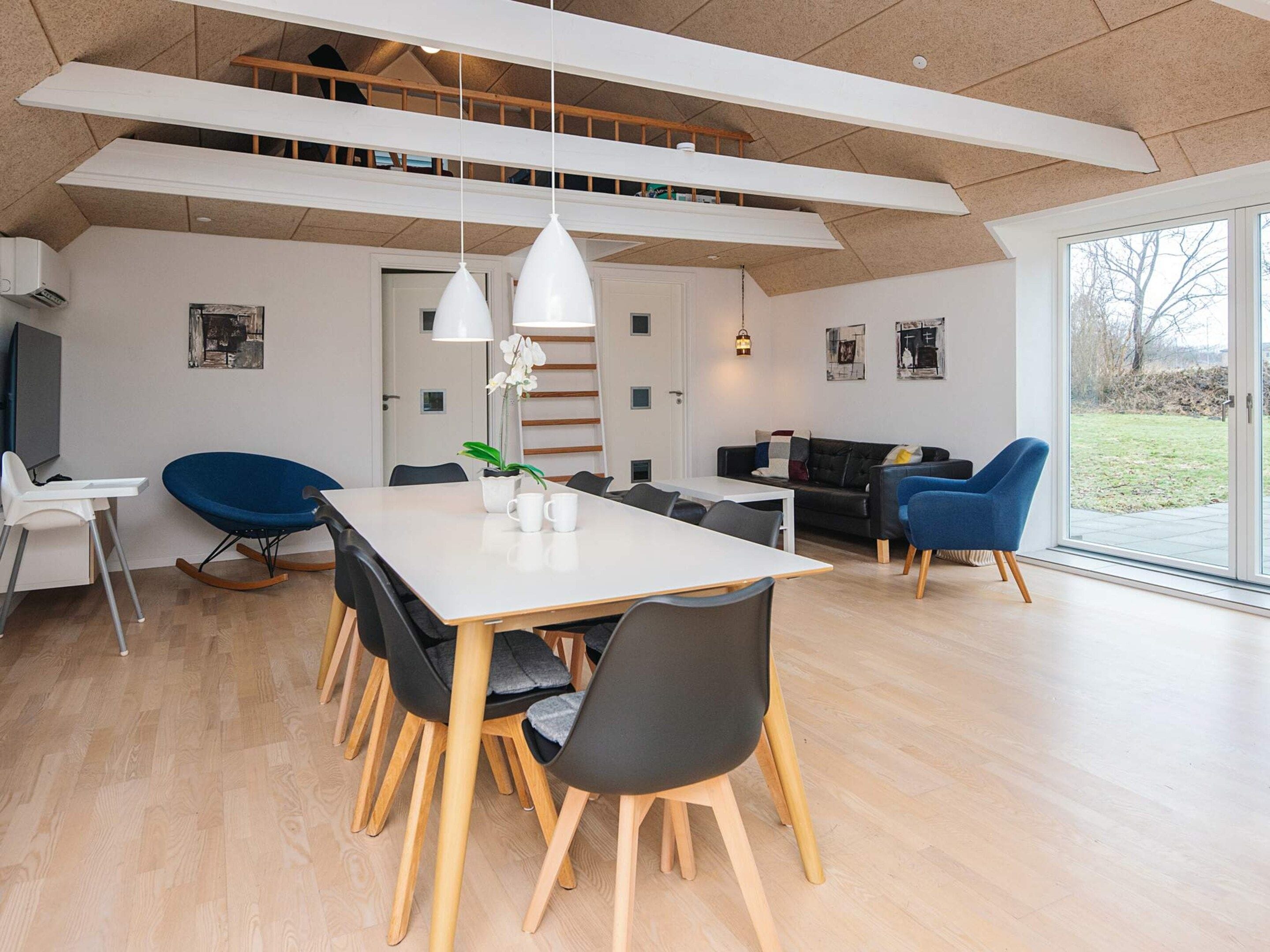 Een moderne eethoek met een witte tafel, zwarte stoelen en een blauwe schommelstoel.