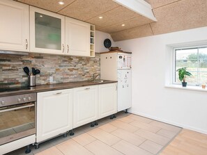 A kitchen with white cabinets, a stone backsplash, a stainless steel stove, and a refrigerator with a WiFi symbol. - Holiday Home in LÃ¸kken (Lokken)