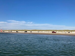 A beach with a row of caravans and a lighthouse in the background. - Holiday Home in LÃ¸kken (Lokken)