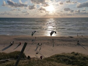 En strand med folk, en drake och havet.