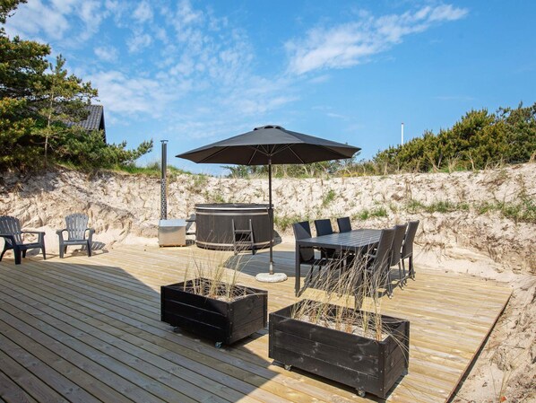 A wooden deck with outdoor furniture, including chairs and a table, and a hot tub.