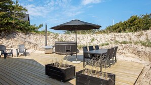 A wooden deck with outdoor furniture, including chairs and a table, and a hot tub. - Holiday Home in Blokhus (Blokhus)