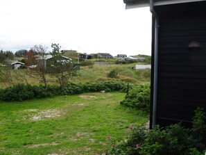 A residential area with houses, a grassy yard, and a pathway leading to a gate.