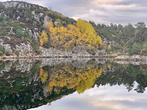 A calm lake reflecting a mountainous landscape with autumn-colored trees.
