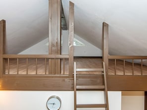 Un dormitorio tipo loft con una escalera de madera, tragaluces y un reloj fijado a la pared.