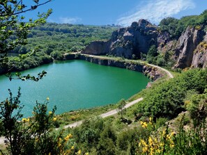 Un paisaje natural con un lago, acantilados rocosos y un sendero de tierra.