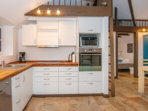 Una cocina compacta con armarios blancos, horno empotrado y cafetera.