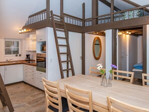 Una cocina con una mesa y sillas de madera, una escalera y un espejo en la pared.