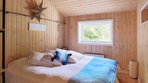 A wooden-paneled bedroom with a bed, a star decoration, a window, and a wall-mounted light fixture. - Holiday Home in Vejby (Vejby)