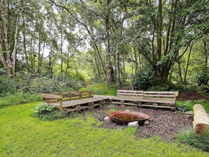 A rustic wooden bench in a lush green forest setting. - Holiday Home in Vejby (Vejby)