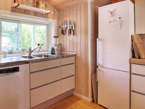 A kitchen with wooden walls, a white refrigerator, a sink, and a blender. - Holiday Home in Vejby (Vejby)