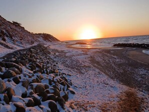 A coastal scene with a rocky shoreline and a sunset. - Holiday Home in Vejby (Vejby)