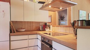A compact kitchen with wooden cabinets, a built-in oven, and a stainless steel range hood. - Holiday Home in Vejby (Vejby)