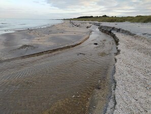 En strand med en smal vattenkanal som skiljer sanden från havet.