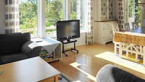 Una sala de estar acogedora con televisor, sofá y mesa de comedor.