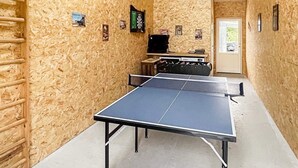 A ping pong table in a room with wooden walls, a door, and a window. - Holiday Home in Dannemare (Dannemare)