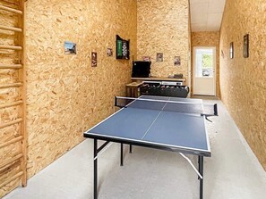 A ping pong table in a room with wooden walls, a door, and a window. - Holiday Home in Dannemare (Dannemare)