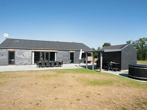 A modern building with a patio area, outdoor seating, and a barbecue setup.