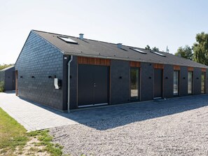 A modern building with a sloped roof, large doors, and a gravel driveway.