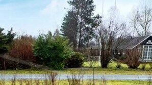 A rural landscape with a house, trees, and a body of water. - Holiday Home in Dannemare (Dannemare)