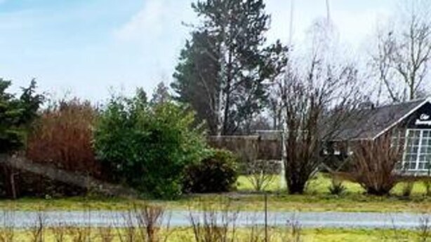 A rural landscape with a house, trees, and a body of water. - Holiday Home in Dannemare (Dannemare)