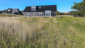 A modern, two-story house with a sloped roof, large windows, and a deck. - Holiday Home in Skagen (Skagen)