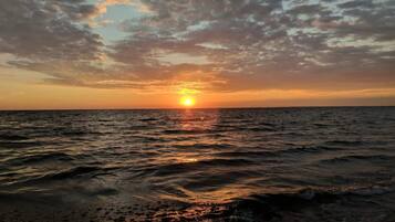 Un coucher de soleil sur l’océan, avec des vagues.