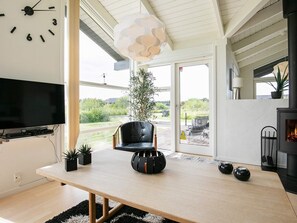 Una sala de estar moderna con un televisor de pantalla plana grande, una mesa de comedor de madera, un sillón de cuero negro y una chimenea.