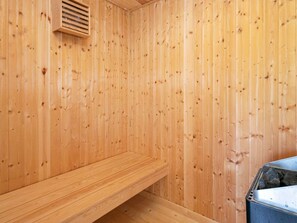 Una sauna de madera con un banco y un calentador.
