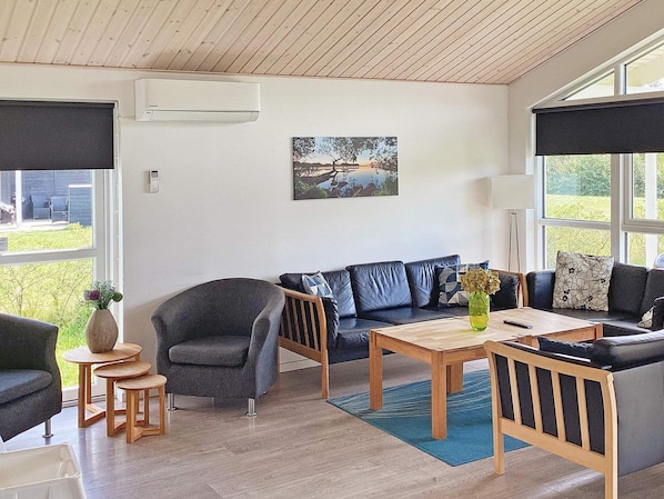 A modern living room with a sofa, armchairs, a coffee table, and a painting on the wall.