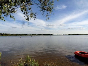 A calm lake with a red kayak docked on the shore. - Holiday Home in Ansager (Ansager)