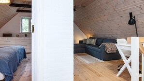 Un dormitorio estilo loft con techo inclinado, una cama, un escritorio y un sofá.