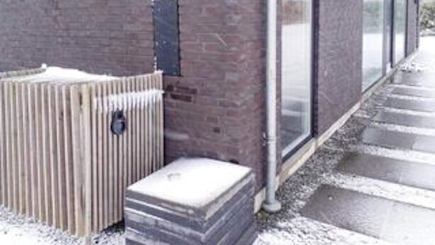 A brick building with a metal fence, a snow-covered ground, and a clear sky. - Holiday Home in Slagelse (Slagelse)