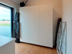 A room with a white wardrobe, a radiator, and a window with curtains.