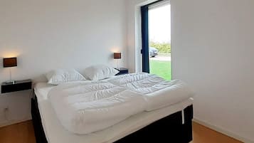 A modern bedroom with a bed, two bedside tables, a window, and a view of the outdoors.