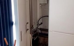 Interieur van een kamer met een deur, een raam met gordijnen en een zichtbaar stopcontact.