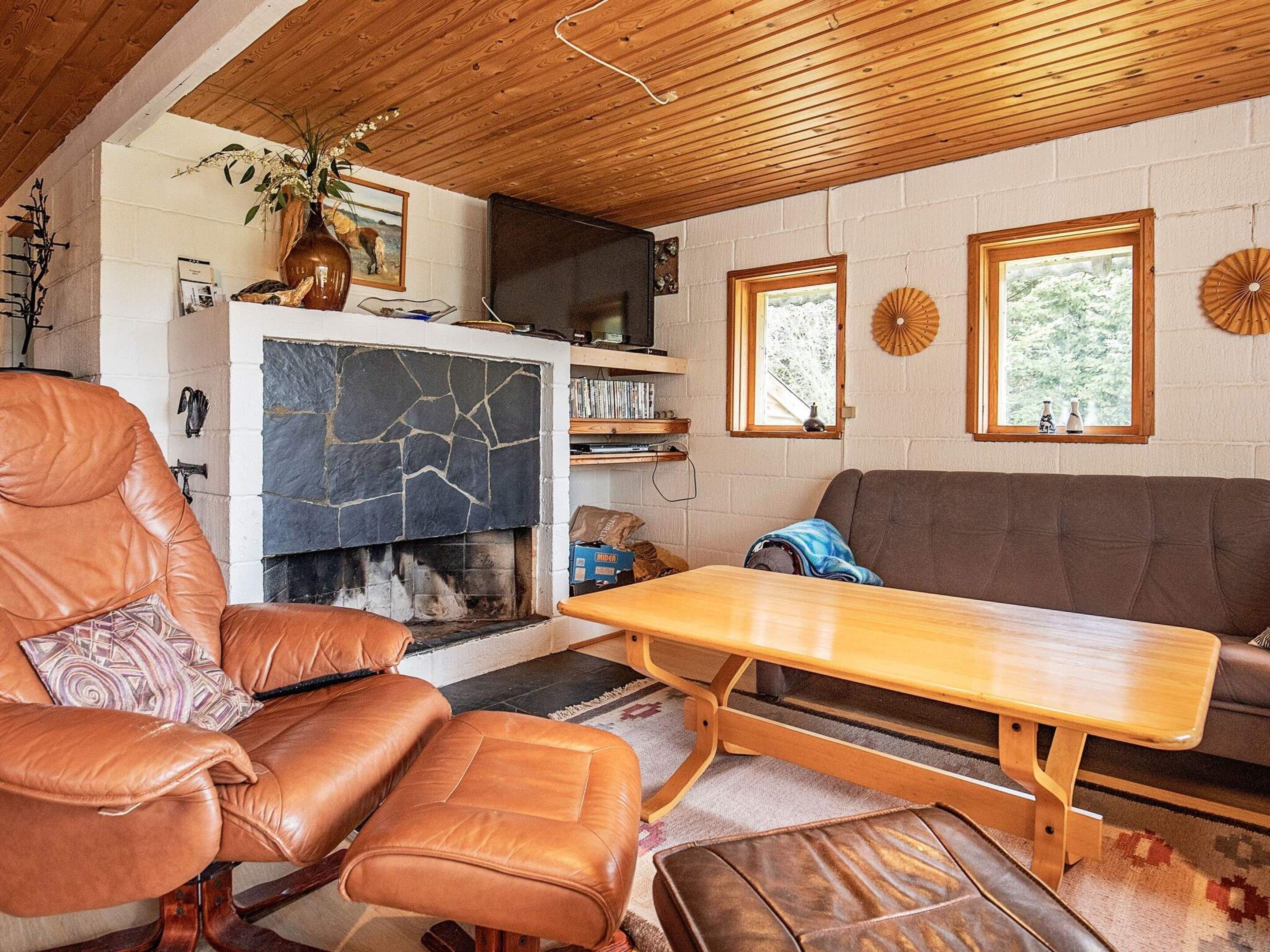 Ein gemütliches Wohnzimmer mit Kamin, Ledermöbeln und einem Fernseher.