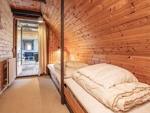 Un interior de madera con una cama, una silla y una mesa.