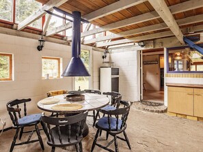 A rustic dining area with a round table, four chairs, and a hanging light fixture.