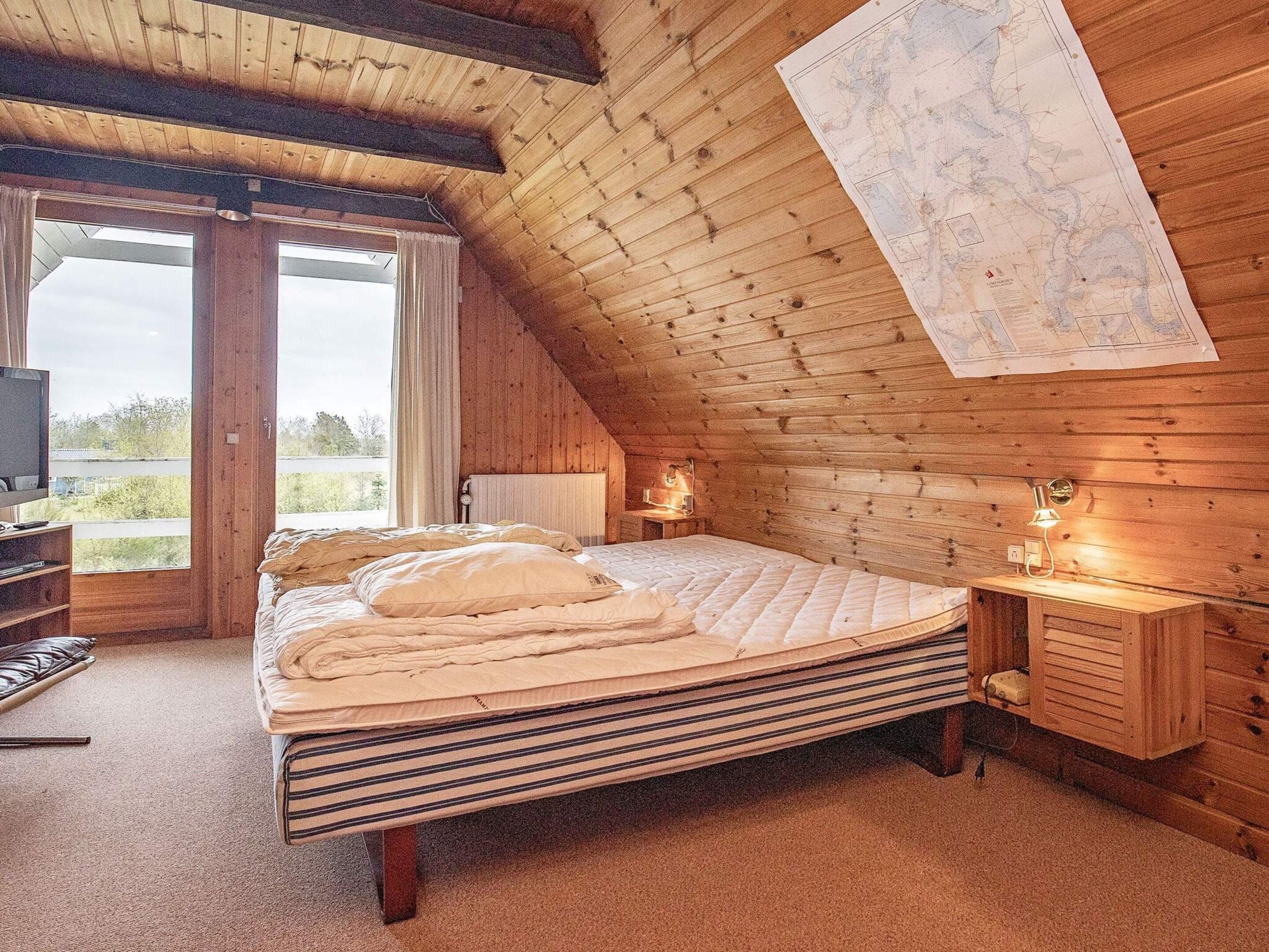 A cozy room with a bed, a desk, and a map on the wall.