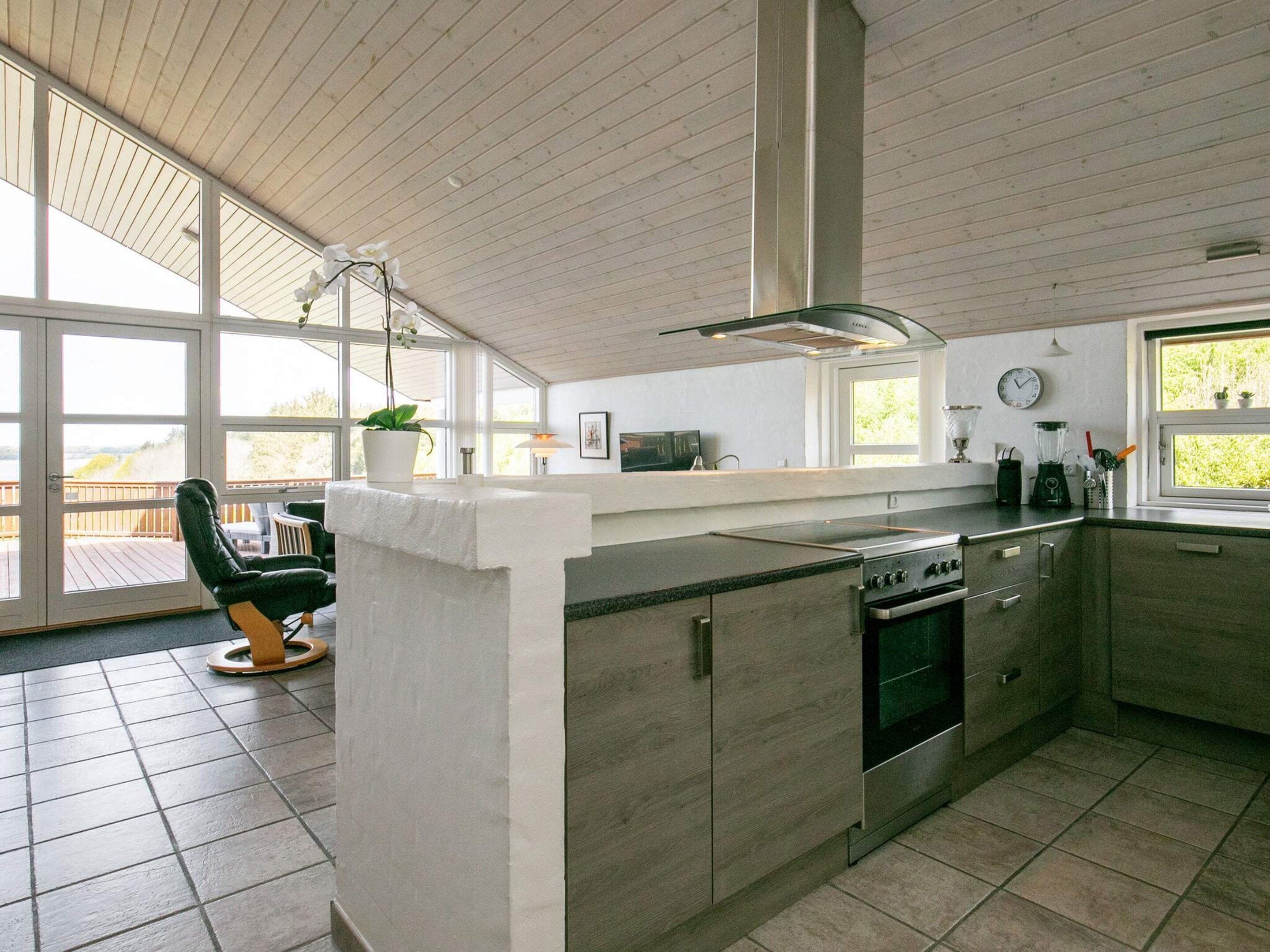 Eine moderne Küche mit einer zentralen Kochinsel, integriertem Backofen und großen Fenstern mit Blick.