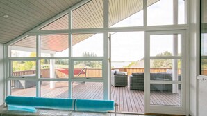A covered outdoor area with a pool, wooden deck, and seating. - Holiday Home in Skals (Skals)