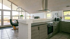 A modern kitchen with a central island, large windows, and a view of the outdoors. - Holiday Home in Skals (Skals)