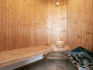 A sauna with wooden walls, a bench, a bucket, and a heater. - Holiday Home in Skals (Skals)