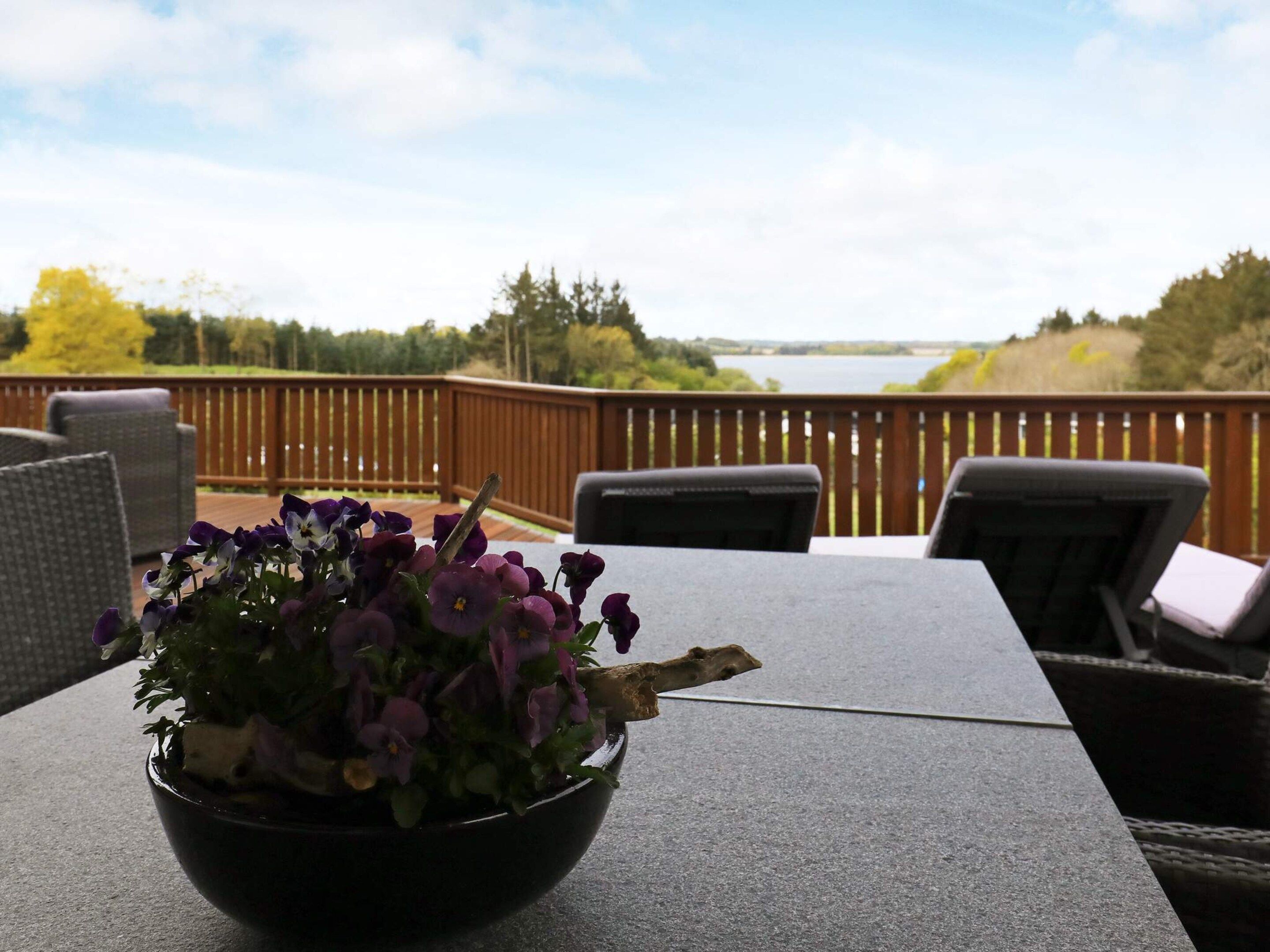 En terrasse med udendørs møbler og udsigt til en sø.