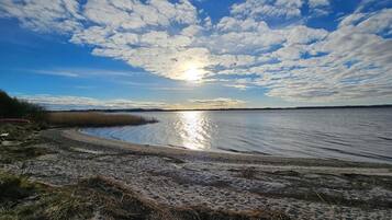 Uma praia com céu claro e o sol refletindo na água.
