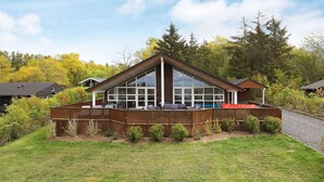 A modern house with a large deck, a covered patio, and a view of a forested area. - Holiday Home in Skals (Skals)