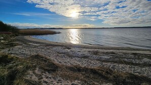 A beach with a clear sky and the sun reflecting on the water. - Holiday Home in Skals (Skals)