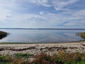 A calm body of water with a sandy shoreline and sparse vegetation. - Holiday Home in Skals (Skals)